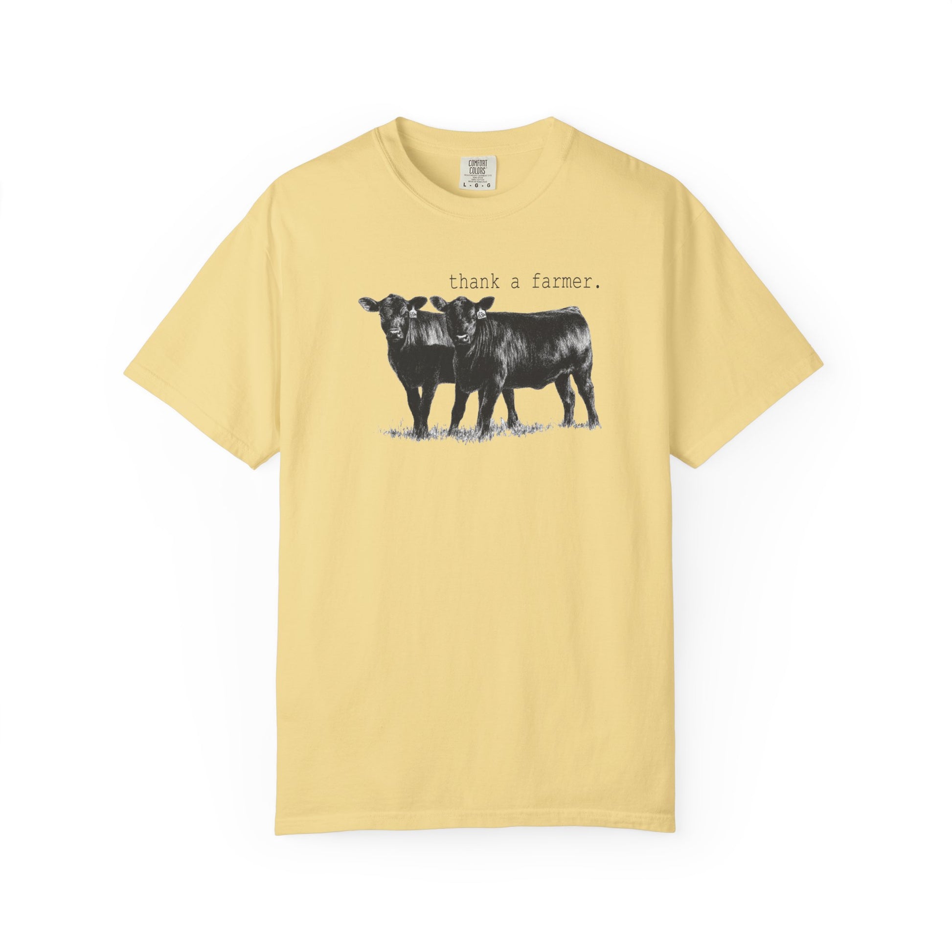 Yellow t-shirt with black and white cow graphic and text 'thank a farmer' on a white background